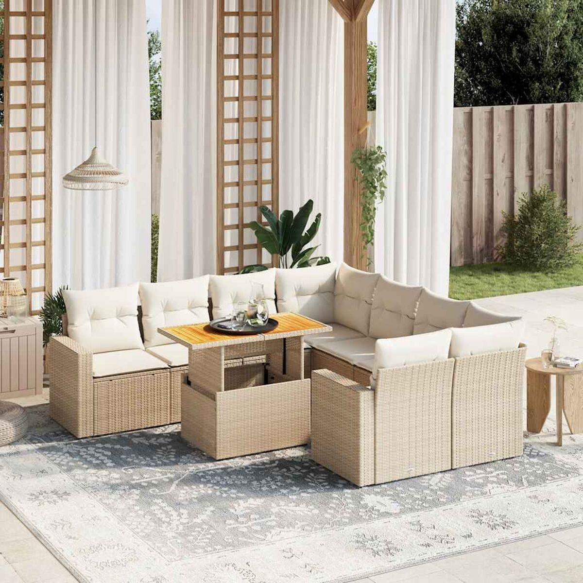 Divano componibile in vimini da esterno con cuscini beige. Un tavolo in legno è al centro. Tende e tappeto sono visibili.