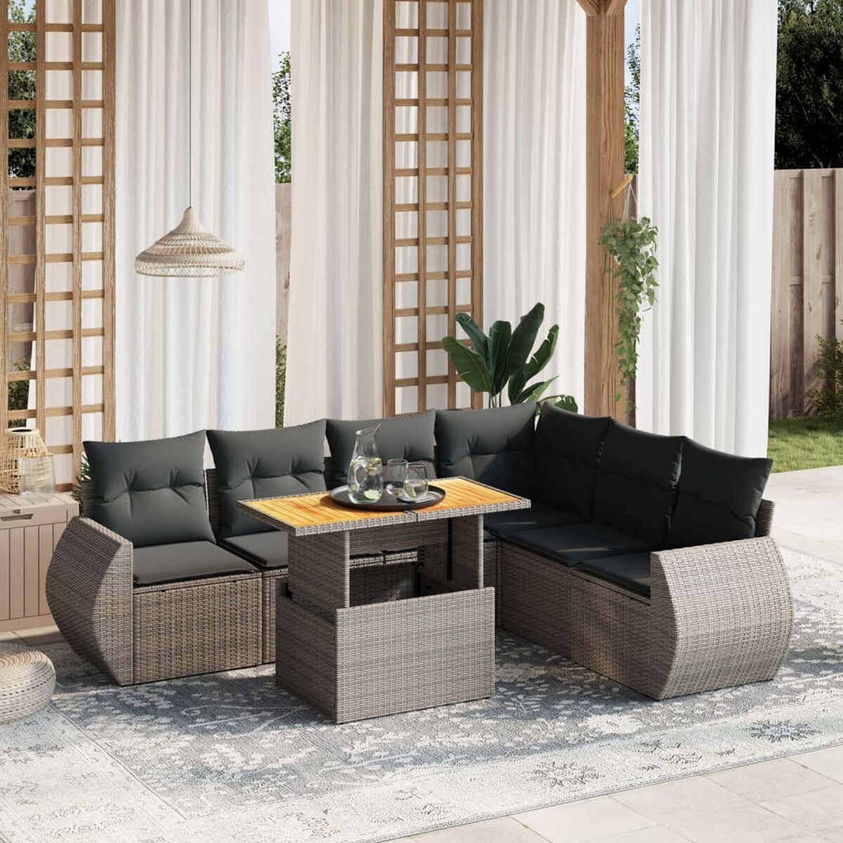 Graues Outdoor-Ecksofa aus Korbgeflecht mit Tisch mit Hubfunktion. Teppich und Vorhänge.