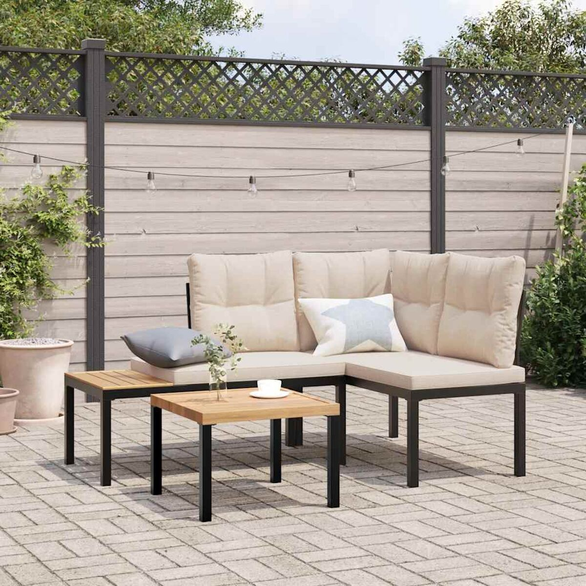 Outdoor-Sitzbereich mit beigen Kissen, Holztisch, Pflanzen und einem Zaun.