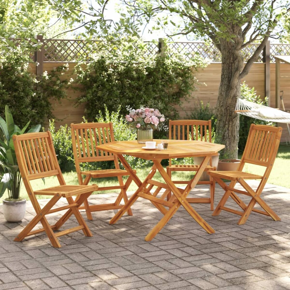 Ein hölzernes Outdoor-Tisch- und Stuhlset auf einer Ziegelterrasse, umgeben von Bäumen.