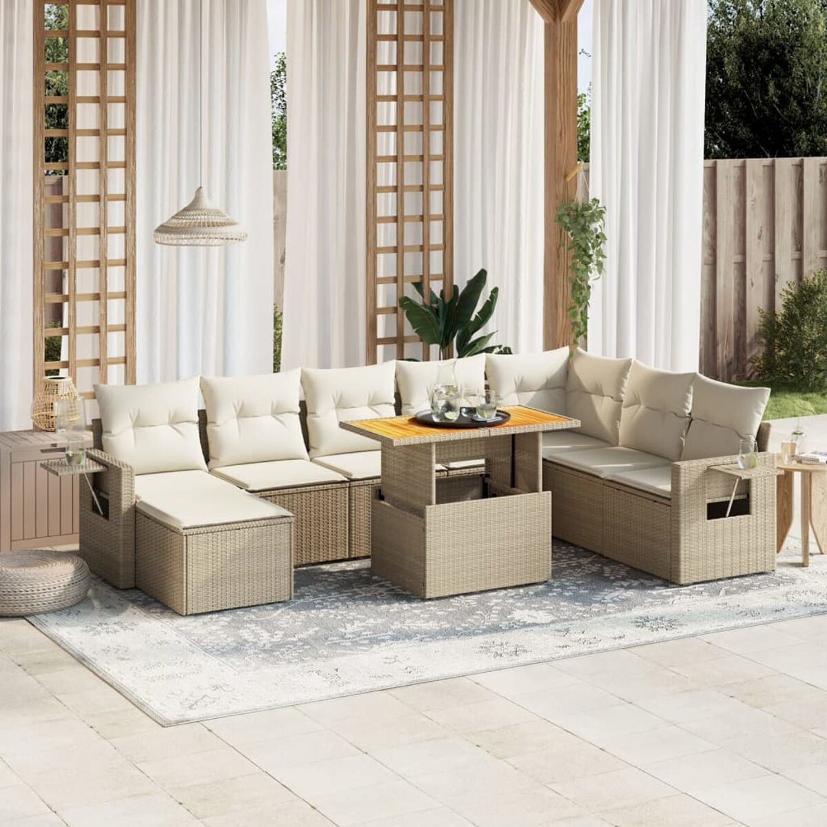 Set divani da esterno con tavolo elevabile. Mobili in rattan beige con cuscini bianchi. Tende e tappeto.