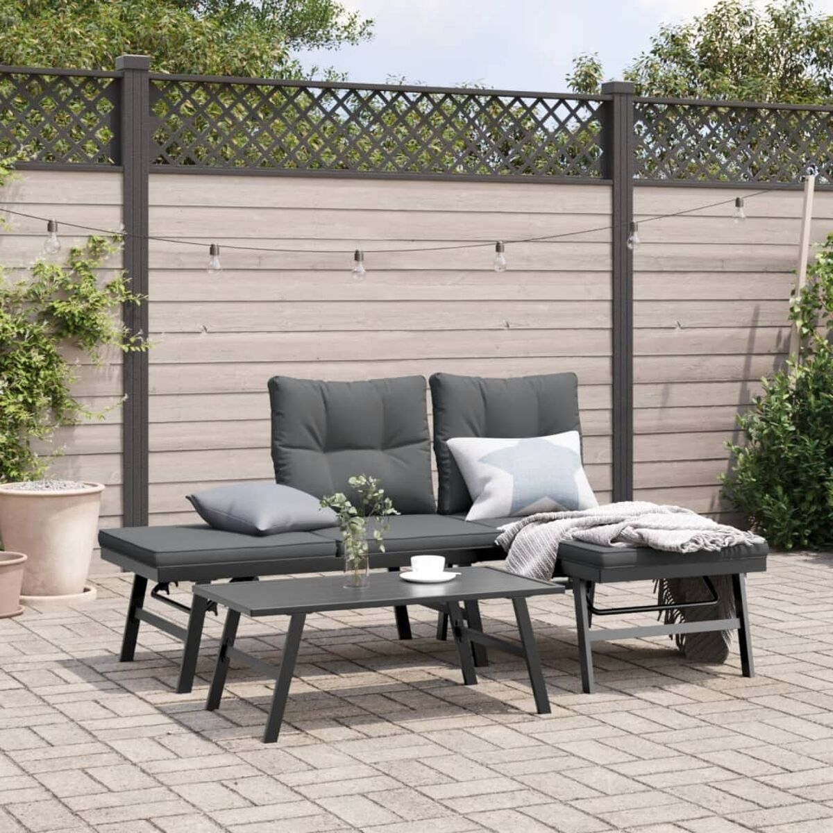 Terrassenmöbel-Set. Graue Kissen, kleiner Tisch und Accessoires auf Ziegelpflaster. Garten.