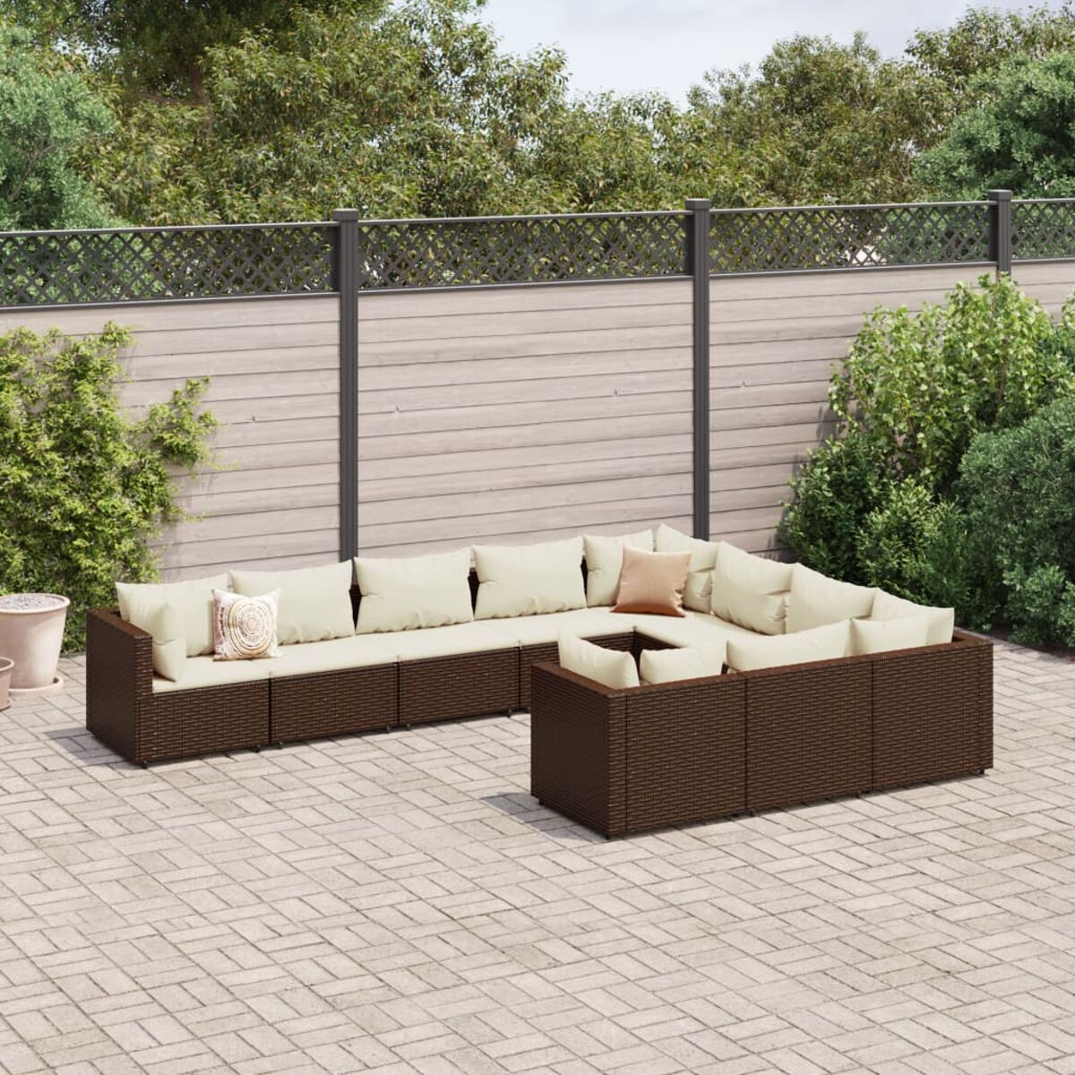 Geflochtene Outdoor-Sitzgruppe mit Kissen und Tisch im Garten.