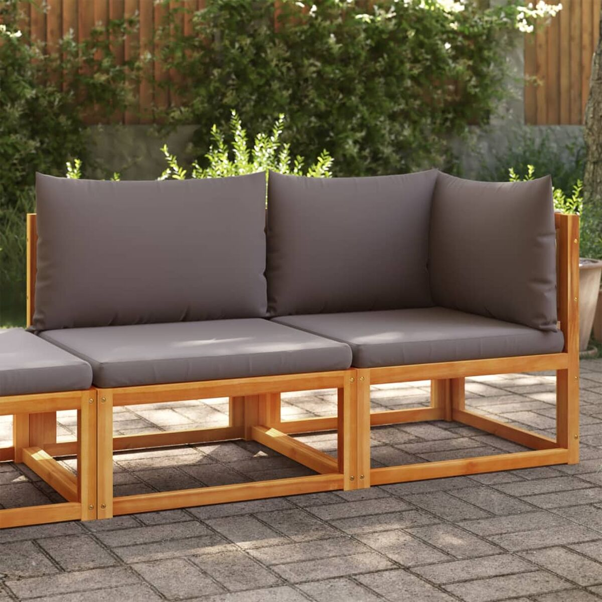 Modulares Outdoor-Sofa mit grauen Kissen auf einem Ziegel-Patio.