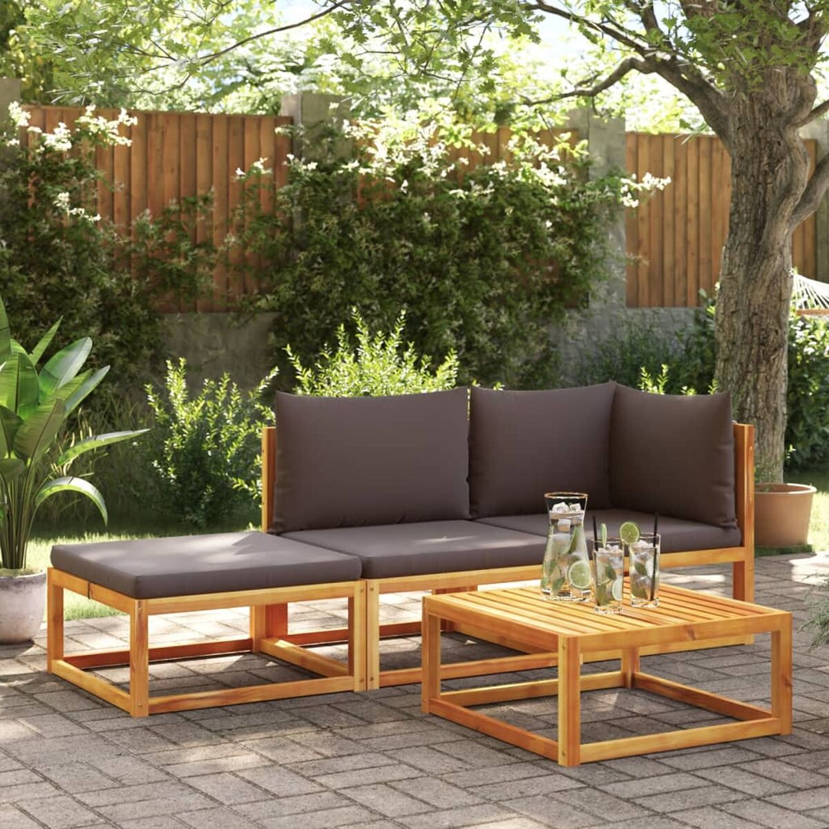 Garnitur aus Holz für draußen. Braune Kissen, Tisch und Garten im Hintergrund.
