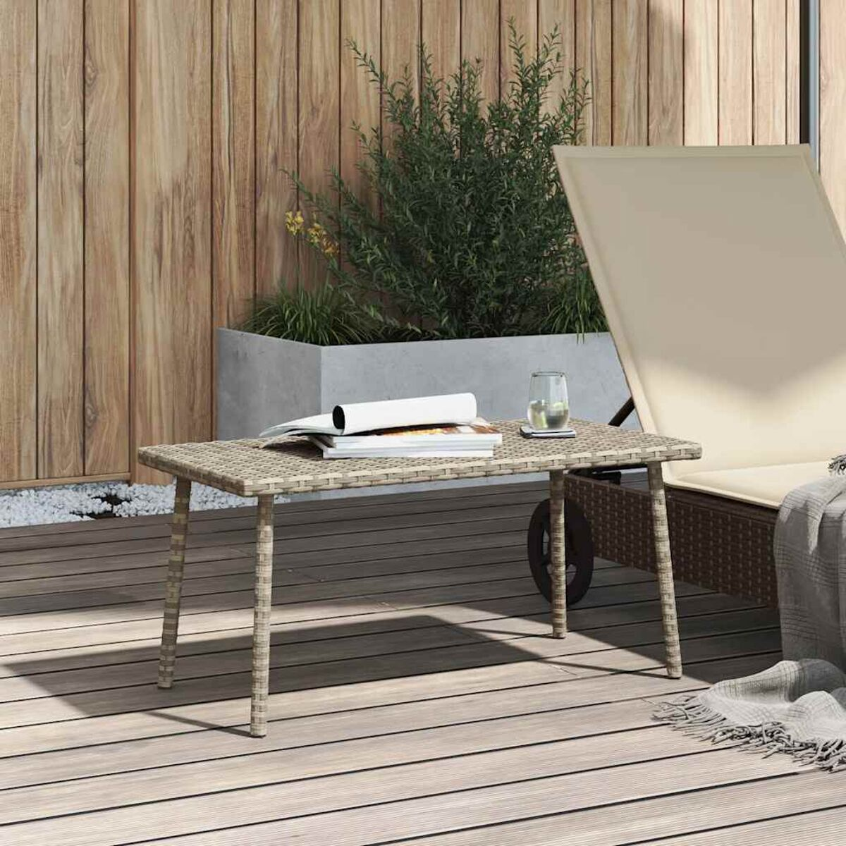 Rattan-Couchtisch auf einem Holzdeck mit Zeitschrift und Glas. Sonnige Umgebung im Freien.