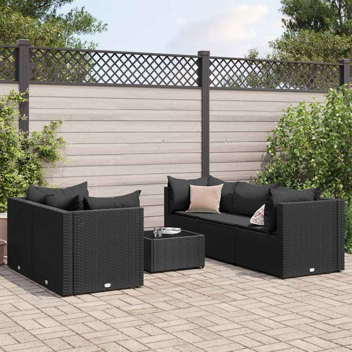 Schwarzes Rattan-Sitzmöbel-Set für den Außenbereich mit einem Couchtisch. Das Set steht auf einer Ziegelterrasse.