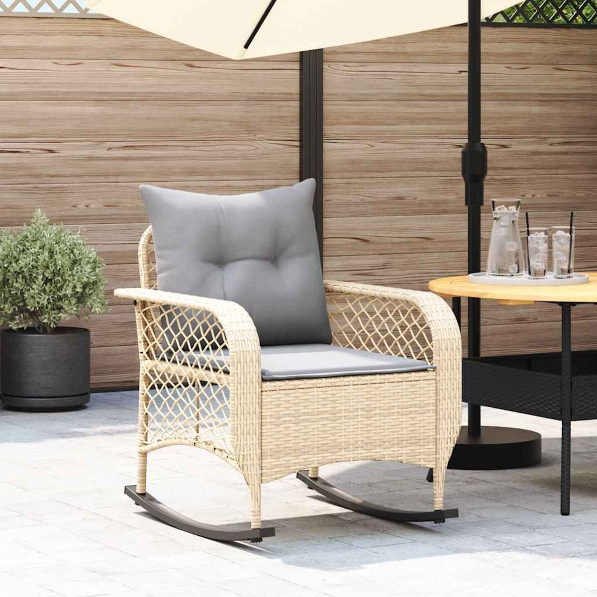 Sedia a dondolo beige con cuscino grigio, tavolino e ombrellone bianco.