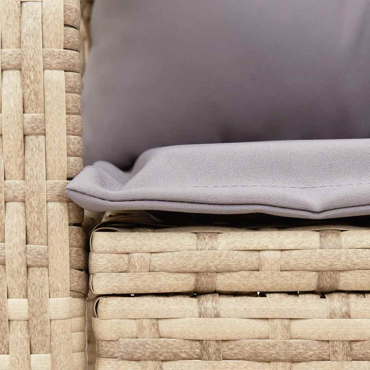 Primo piano di sedia intrecciata con cuscino grigio. Struttura intrecciata beige.