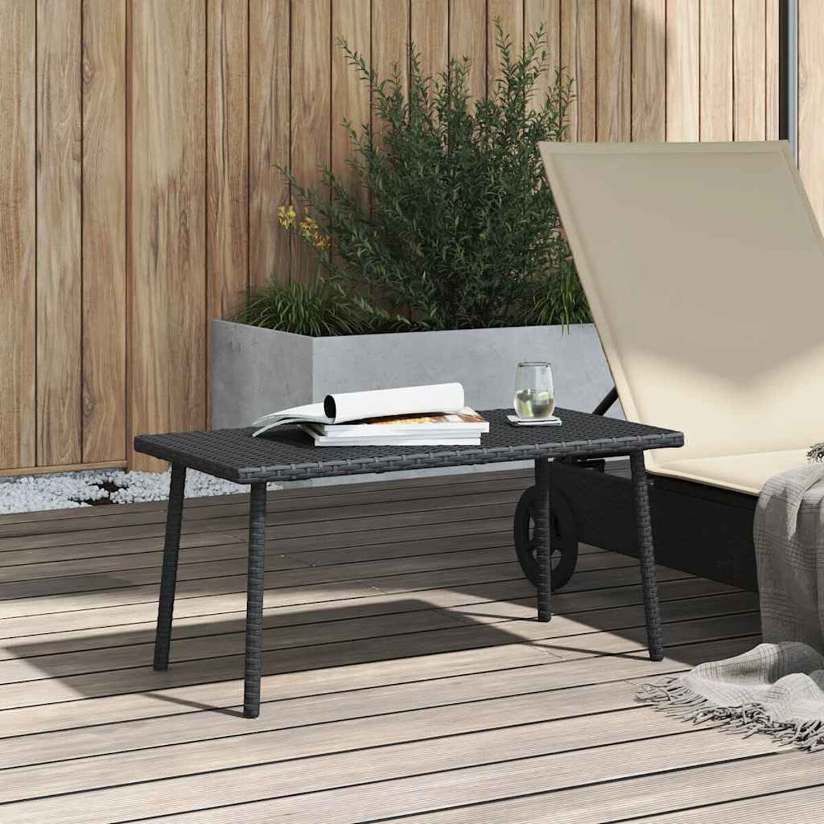 Tavolo nero con sopra oggetti. Sdraio con coperta sullo sfondo. Parete in legno.