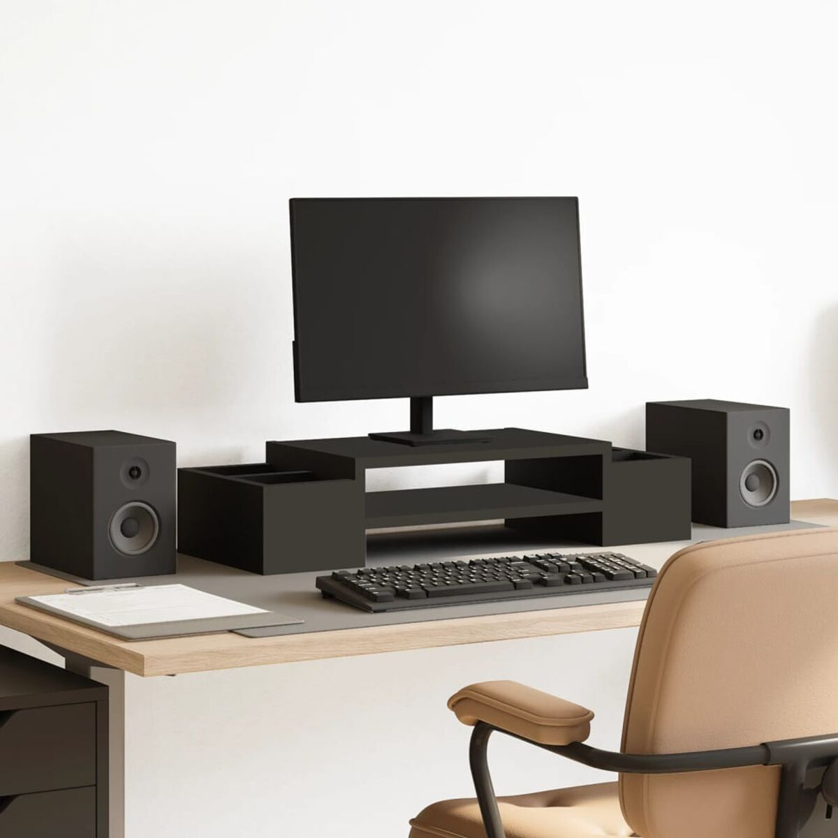 Schwarzes Computer-Setup auf einem hellen Holzschreibtisch. Enthält Monitor, Lautsprecher, Tastatur, Maus und Stuhl.