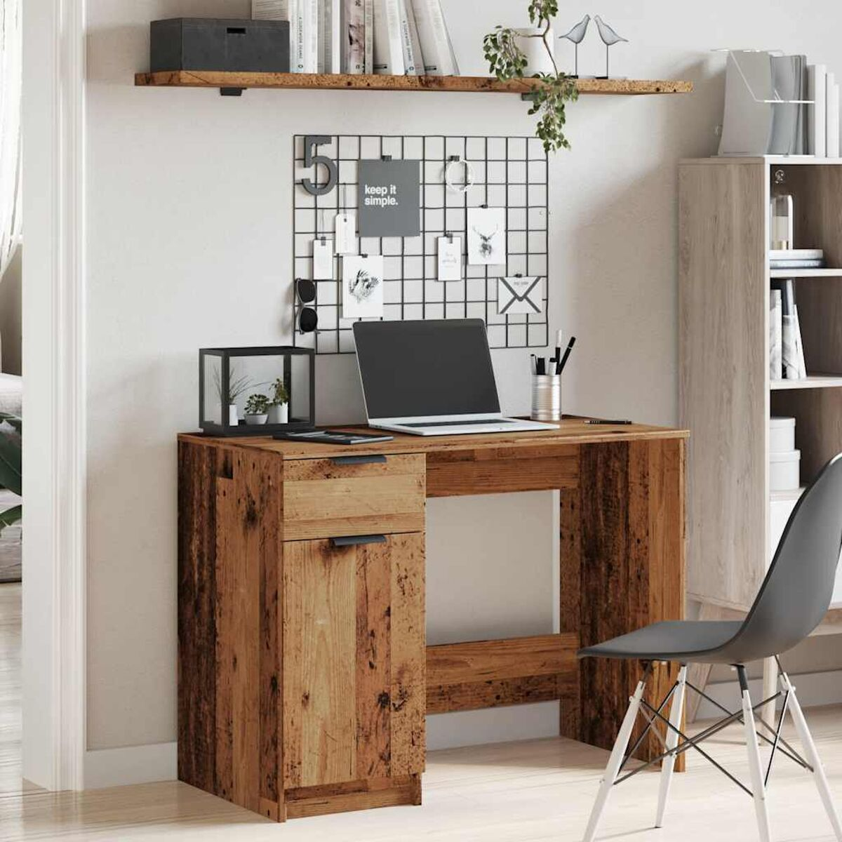 Holzschreibtisch mit Regal, Schublade und Gegenständen darauf. Weißer Wandhintergrund.