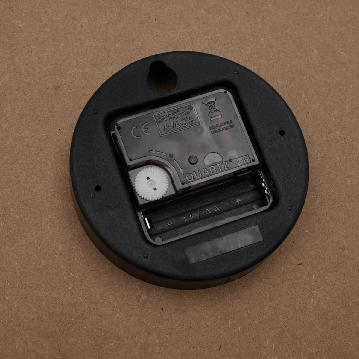Uhrwerk mit Batteriefach, Zahnrädern und dem Wort 'QUARTZ'.