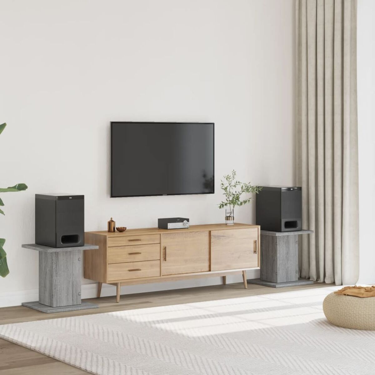 Wohnzimmer-Setup mit Fernseher, Lautsprechern und Konsole. Der Raum hat einen hellen Teppich und neutrale Wände.