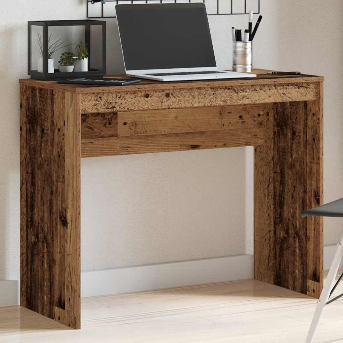 Holzschreibtisch mit Laptop, Stiften und Dekorationsartikeln. Der Schreibtisch ist braun.