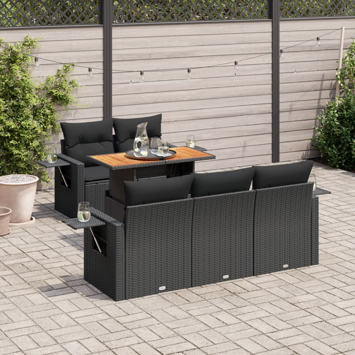 Set di sedute per esterni su un patio pavimentato. Include tavolo, divano e sedia con cuscini.