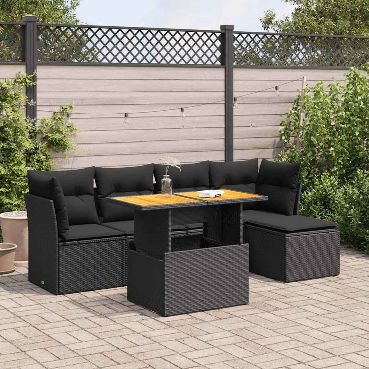 Set divano da esterno in vimini nero con tavolo in legno, su un patio.