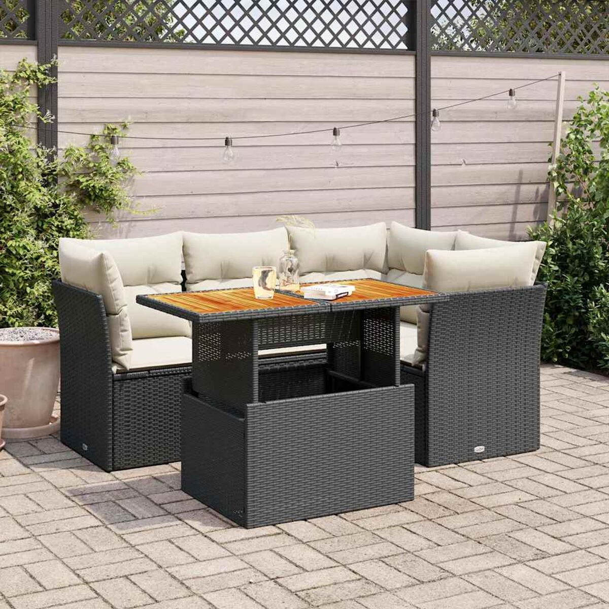 Set di mobili da esterno in vimini grigio scuro con tavolo e cuscini. Ambiente esterno.