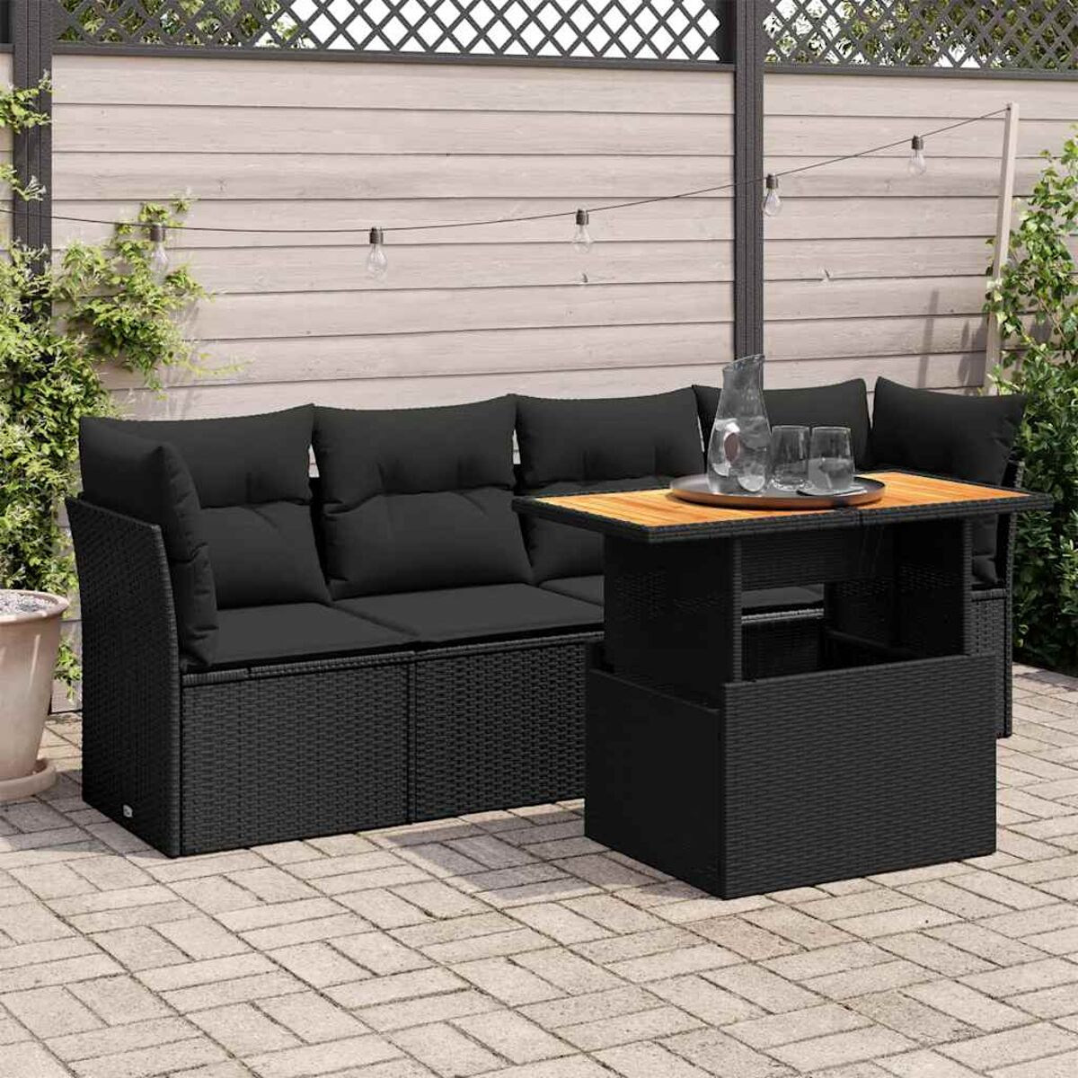 Set divano in rattan nero con tavolo rialzabile su un patio in pietra.