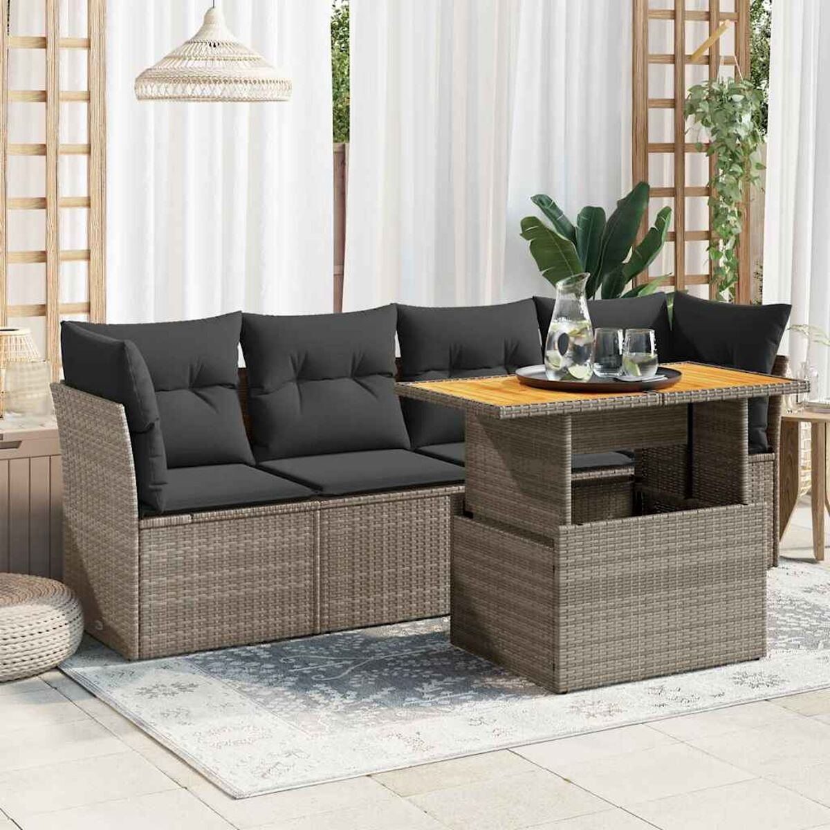 Set di divani in rattan da esterno con un tavolo in legno e un tappeto.