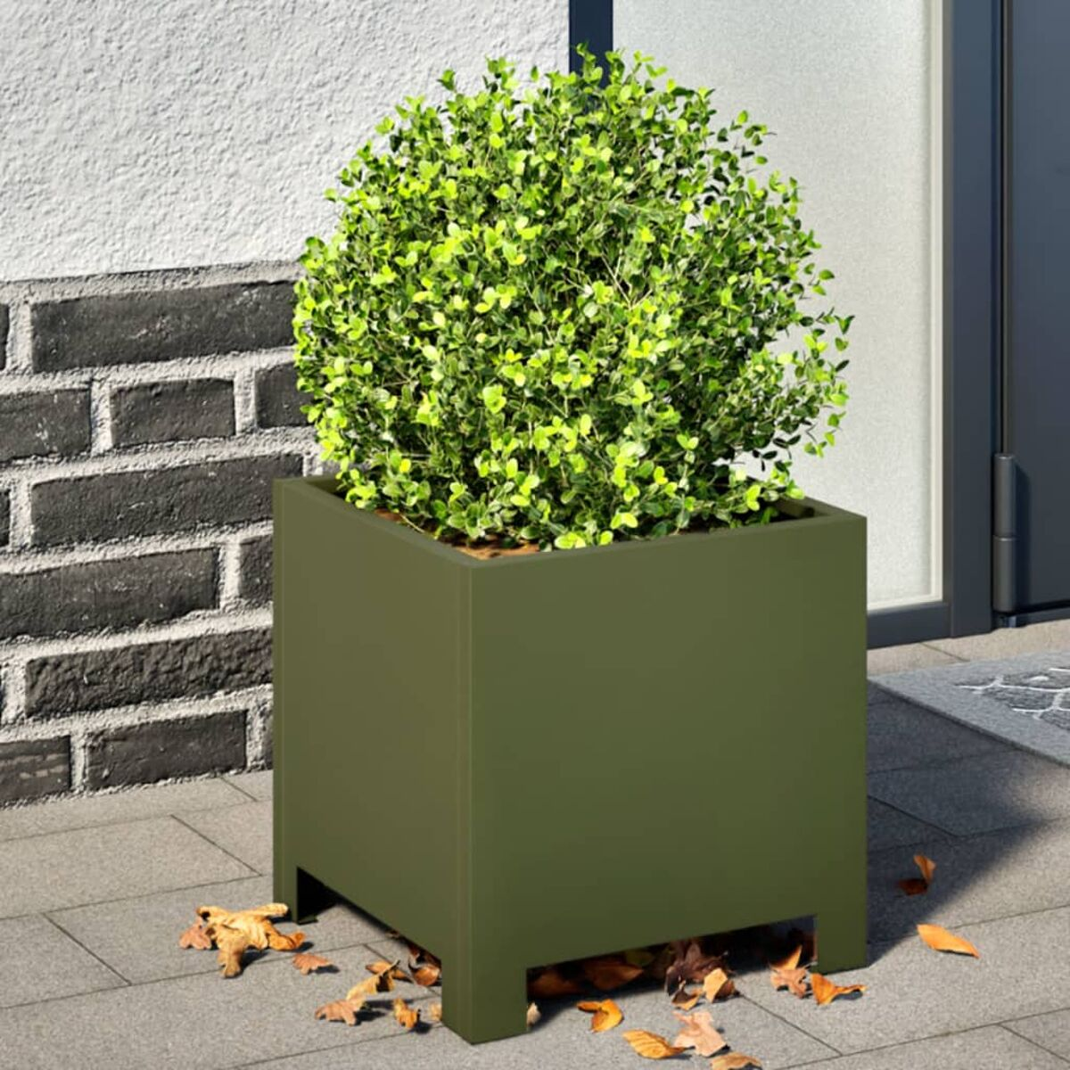 Una fioriera quadrata verde con un topiary, accanto a un muro di mattoni.