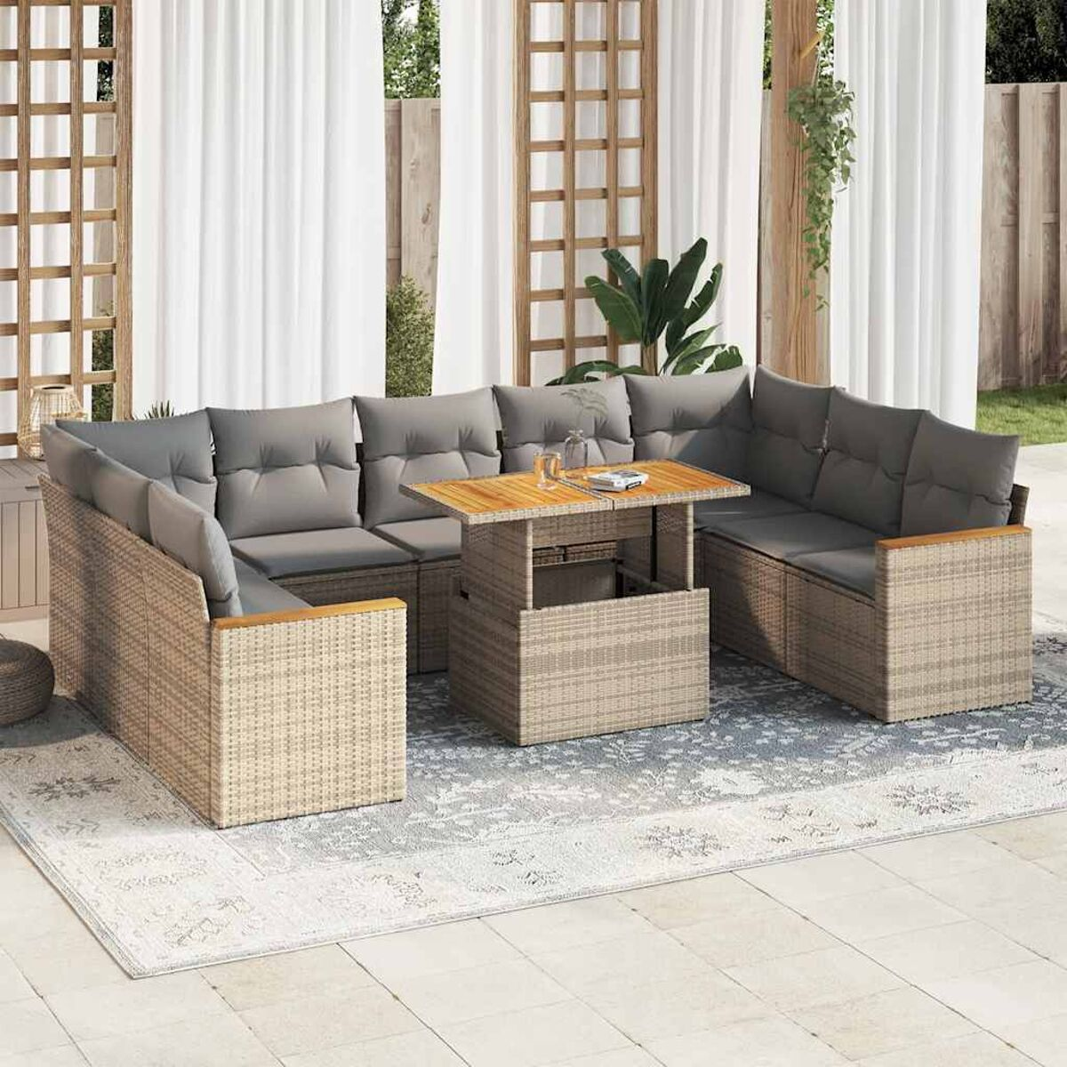 Set di mobili da esterno. Divano in vimini beige, tavolo in legno, cuscini grigi, tende bianche.