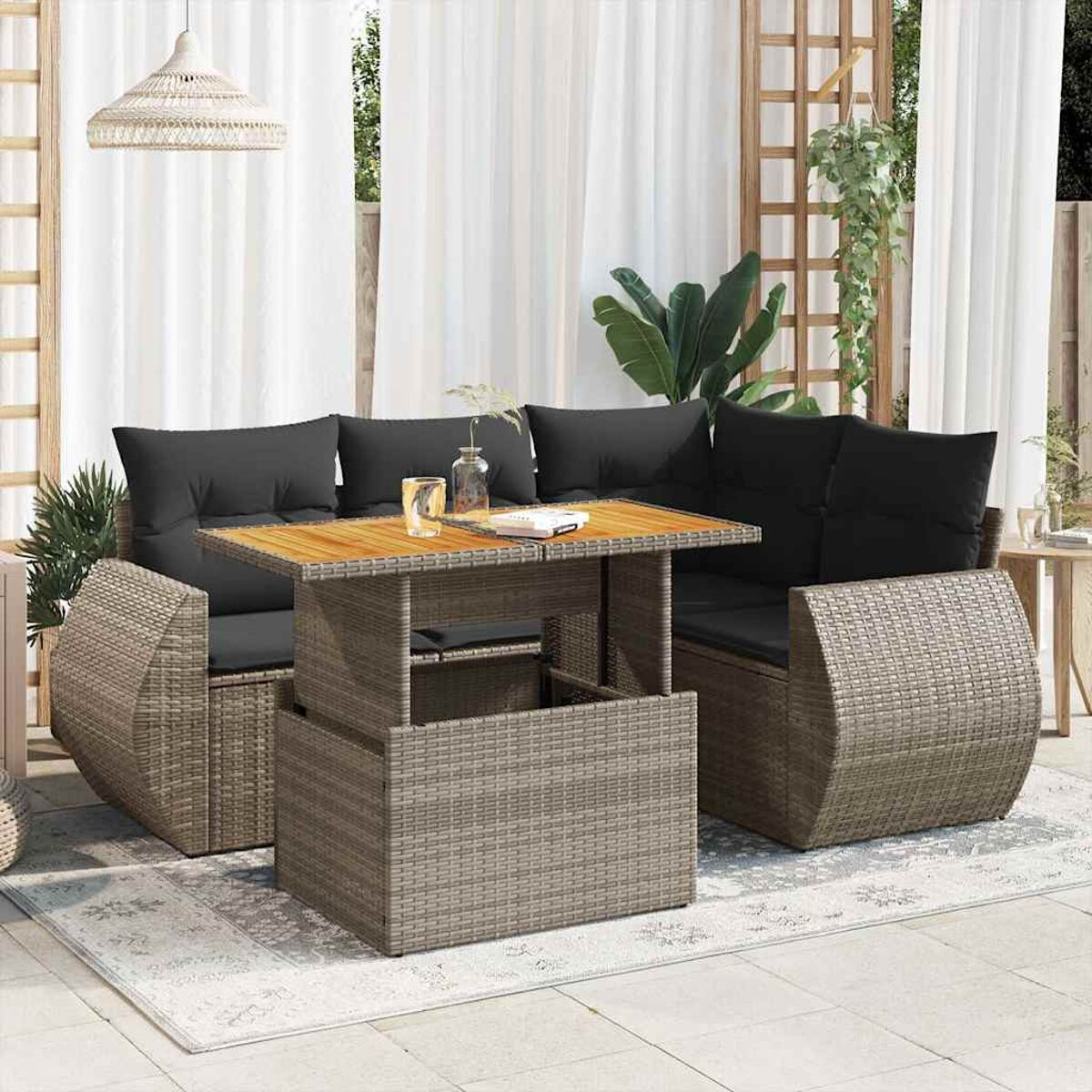 Set divano in rattan da esterno con tavolo, cuscini, bicchieri e un libro.