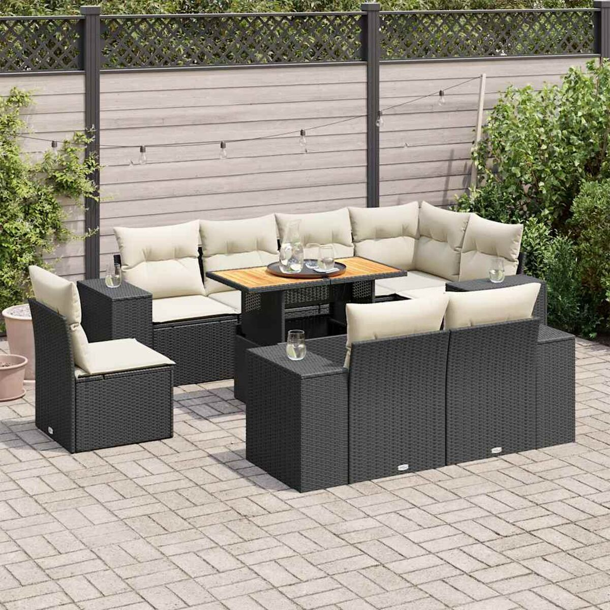 Set divano in rattan nero per esterni. Include tavolo, sedie e divano con cuscini color crema.