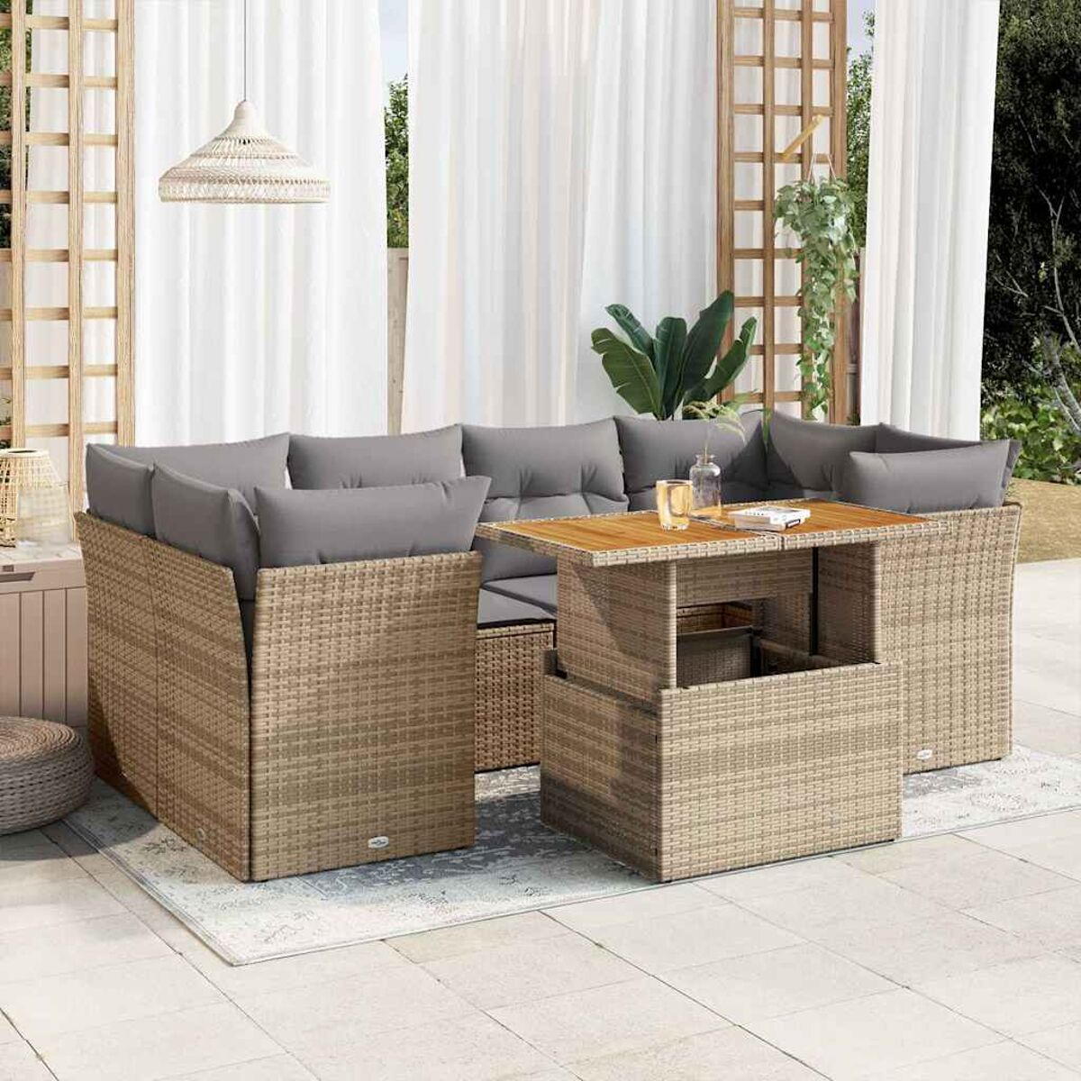 Mobili da esterno in vimini beige con tavolo e cuscini. Ambiente patio con piante.