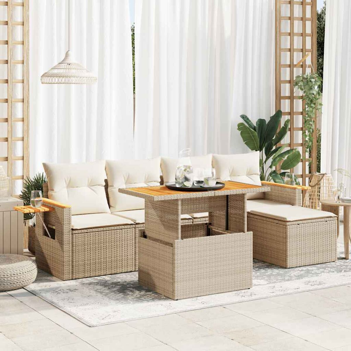 Set divano in vimini da esterno con cuscini e tavolino. Ambiente patio con tende bianche.