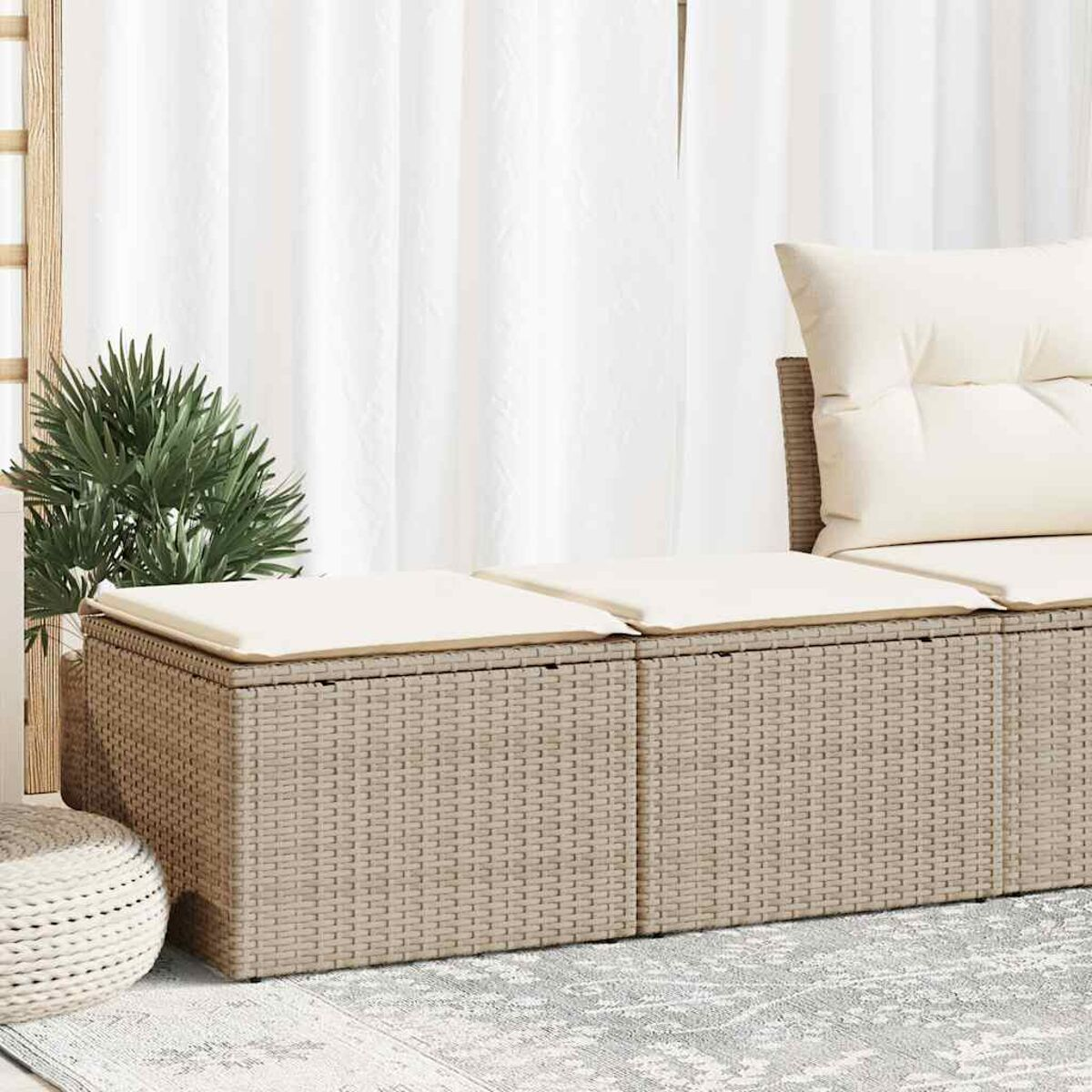 Rattan-Sitzmöbel für den Außenbereich. Beige Kissen und eine kleine Pflanze. Hintergrund: weiße Vorhänge und Sonnenlicht.