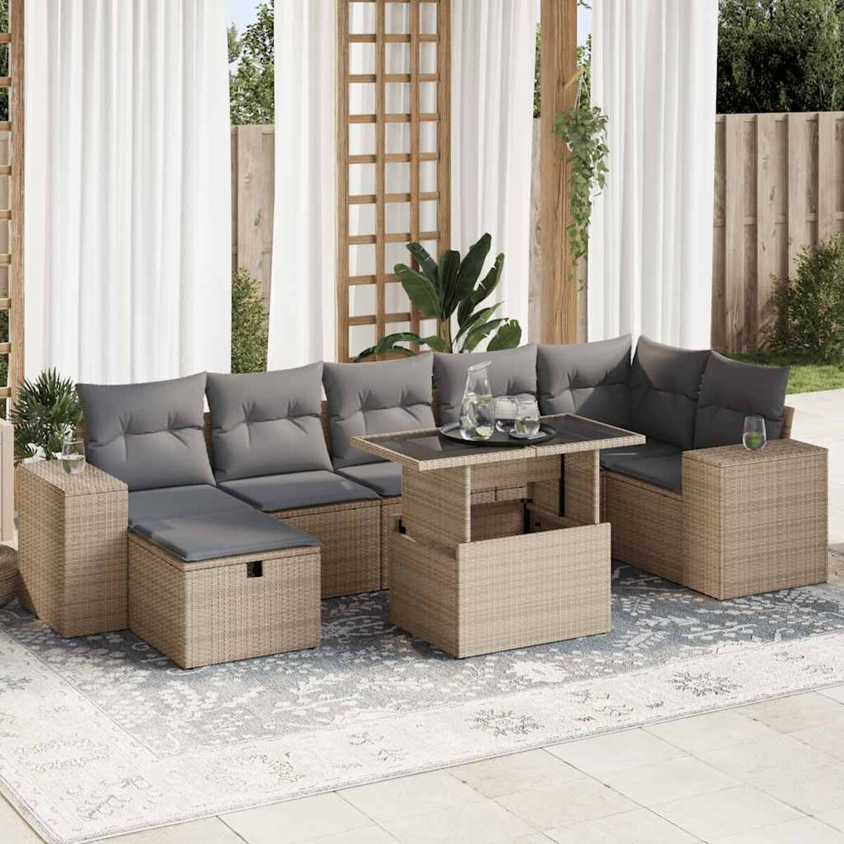 Set divani in rattan con cuscini, tavolo, tappeto. Tende bianche e recinzione in legno.