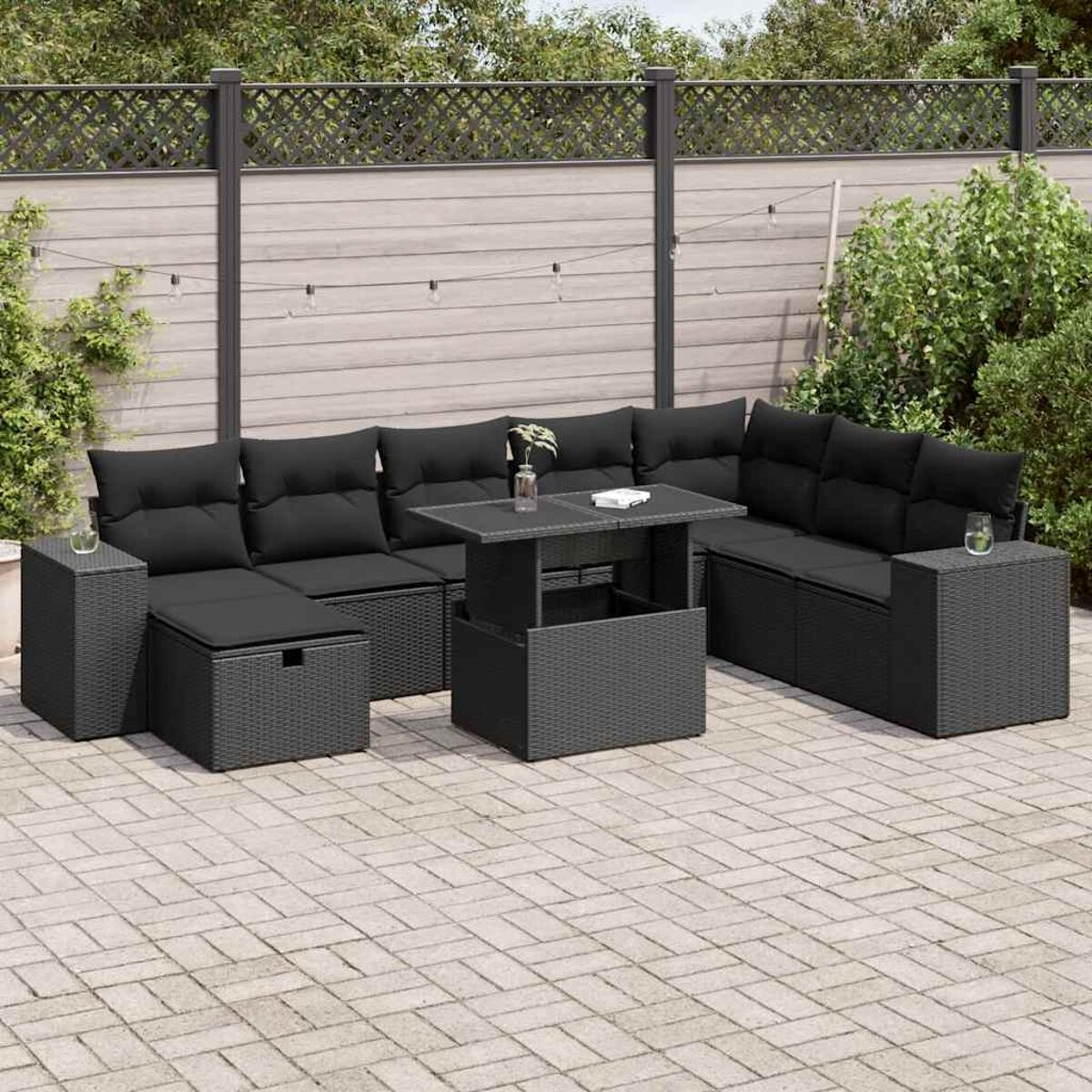 Schwarzes Gartenmöbel-Set mit Kissen, einschließlich Tisch, Sofas und Ottomanen, auf Ziegelpflaster.
