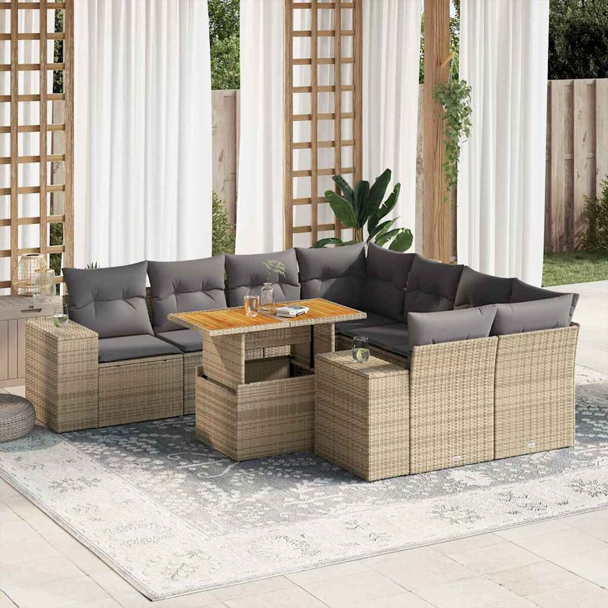 Set divano in rattan da esterno con tavolo, cuscini grigi e tende sullo sfondo.