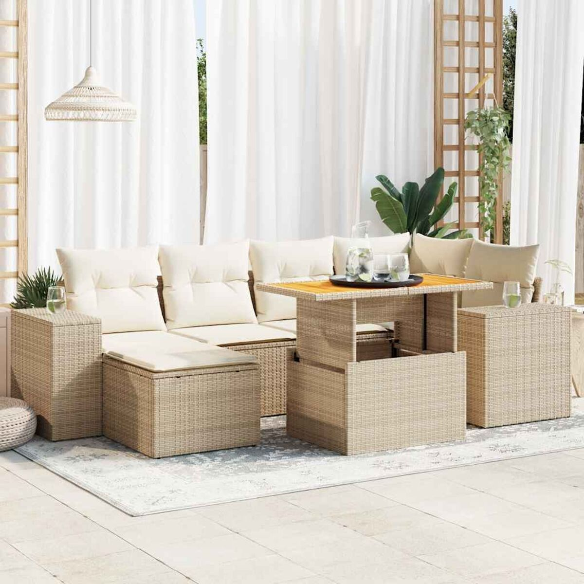 Un set di divani in rattan beige per esterni. Un tavolo è al centro con cuscini. Una tenda bianca sullo sfondo.