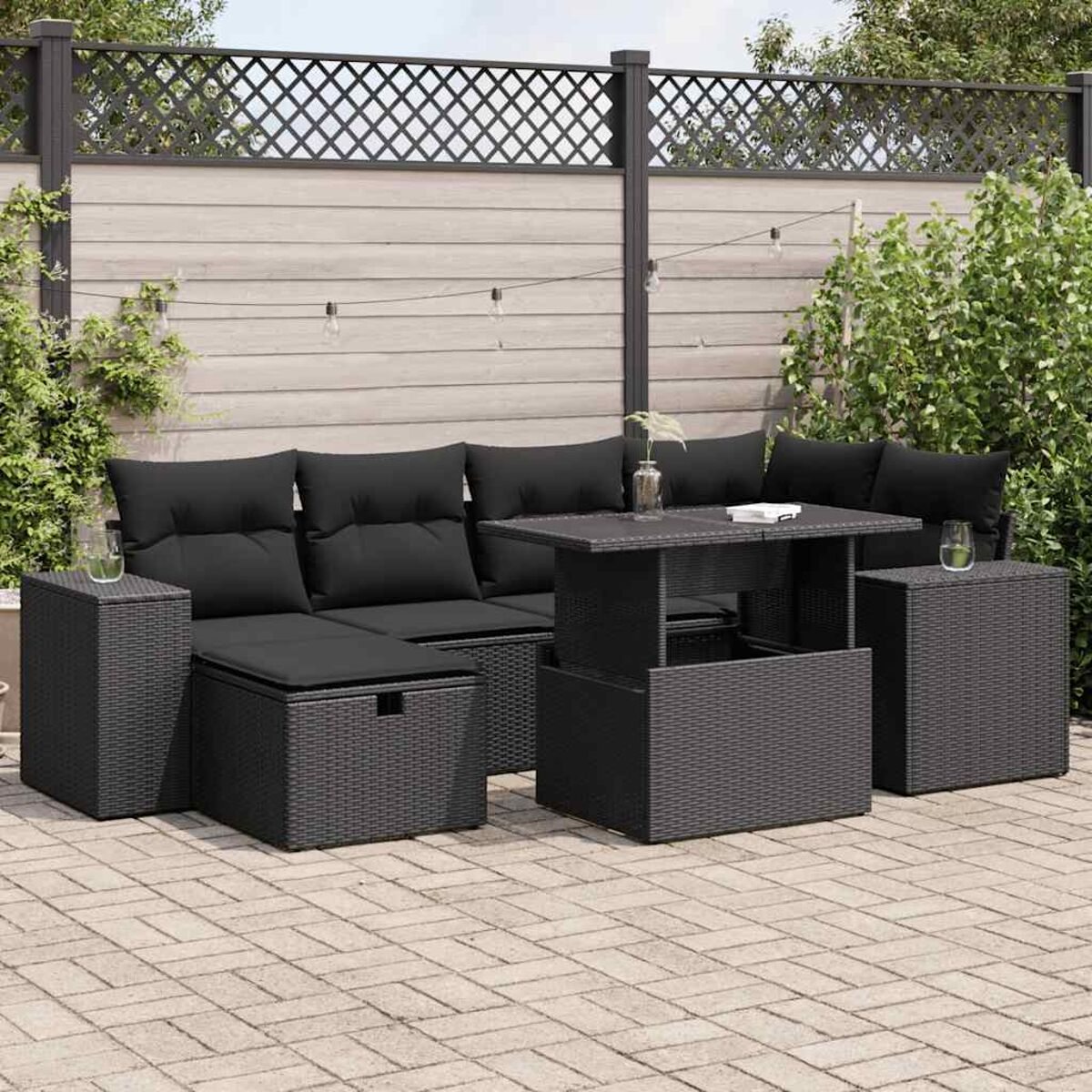 Set di mobili da giardino in rattan nero. Include divano, tavolo e pouf.