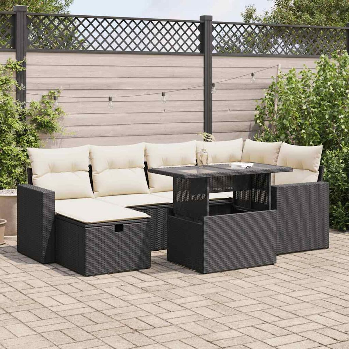 Schwarzes Outdoor-Set aus Korbgeflecht. Enthält Sofa, Tisch und Ottomane. Neutralfarbener Patio und Hintergrund.