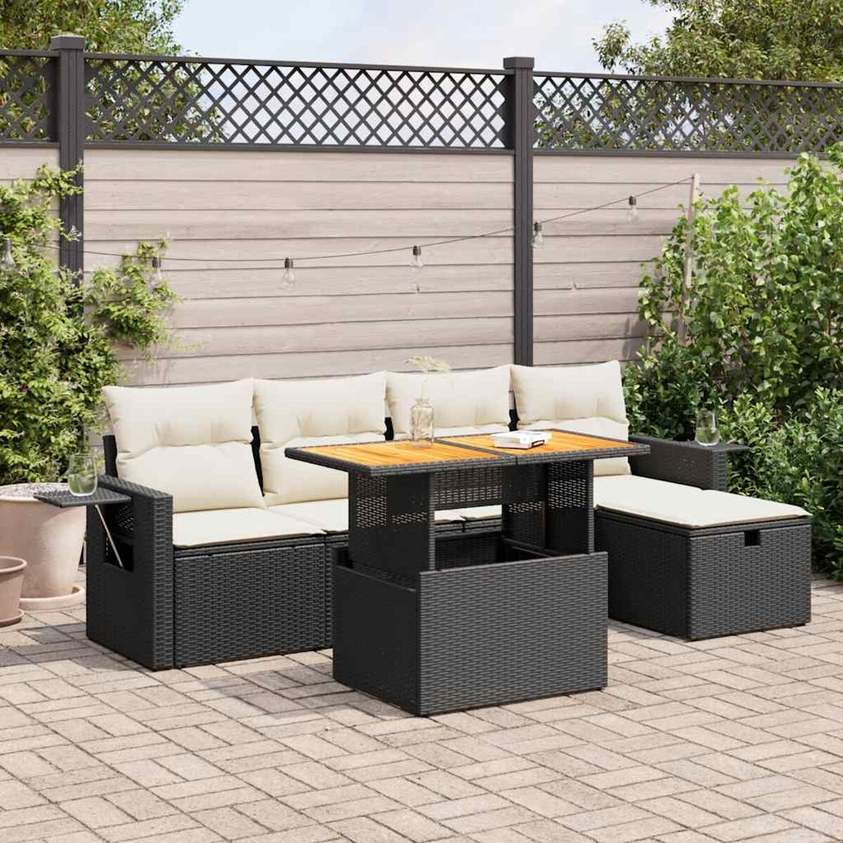 Schwarzes Outdoor-Sofa mit Holztisch auf Terrasse mit Pflanzen.