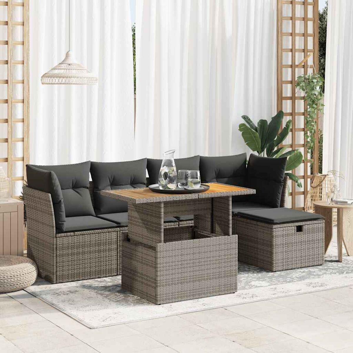 Rattansofa-Set mit Kissen und Tisch. Weiße Vorhänge im Hintergrund. Hellfarbiger Teppich.