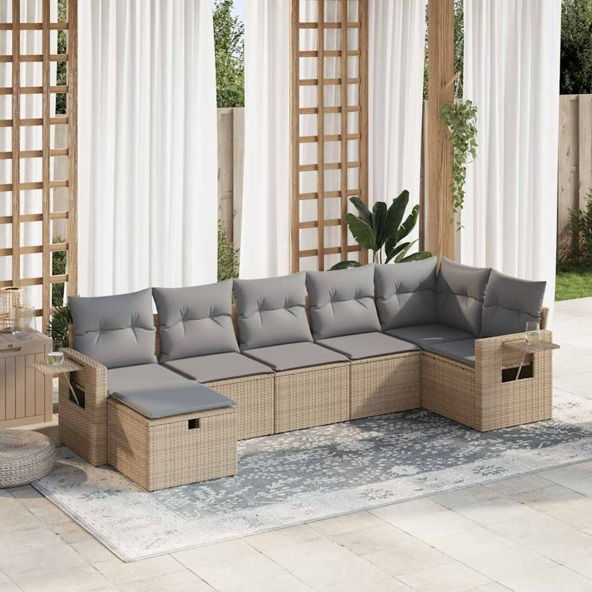 Set divano da esterno in vimini beige con cuscini grigi.