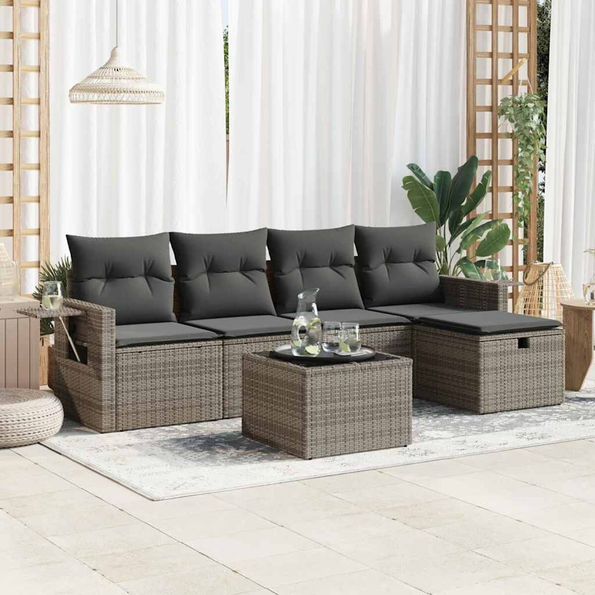 Geflochtene Outdoor-Couch, Couchtisch und Stauraum-Ottomane mit Kissen und Getränken.