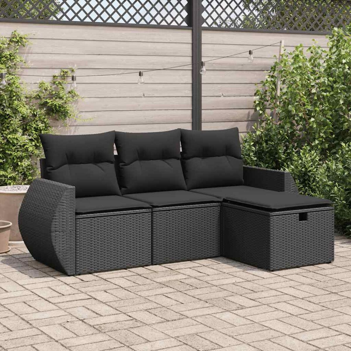 Set divani esterno in rattan nero con cuscini grigi e patio in mattoni.