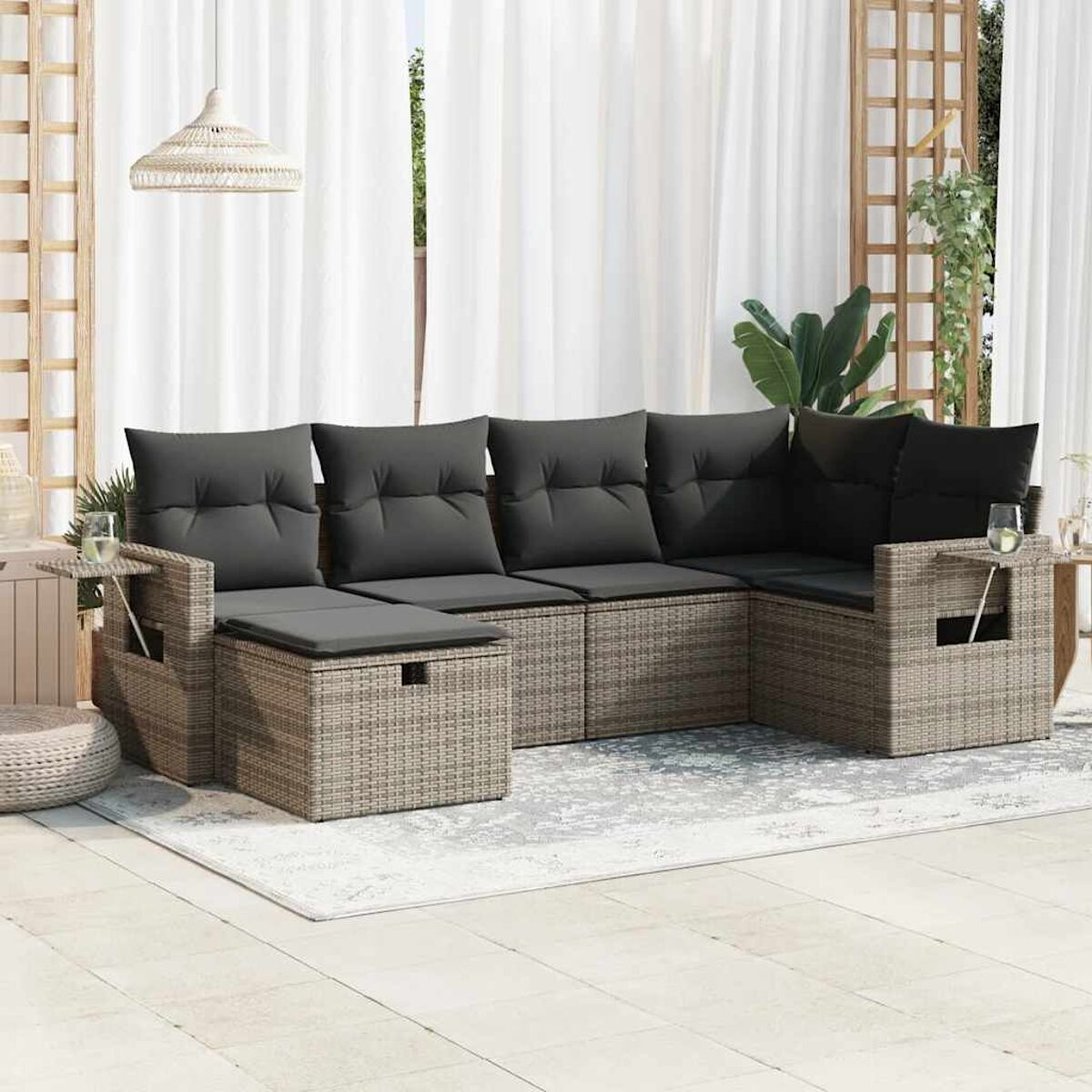 Geflochtener Outdoor-Schnitt mit grauen Kissen und Beistelltischen.