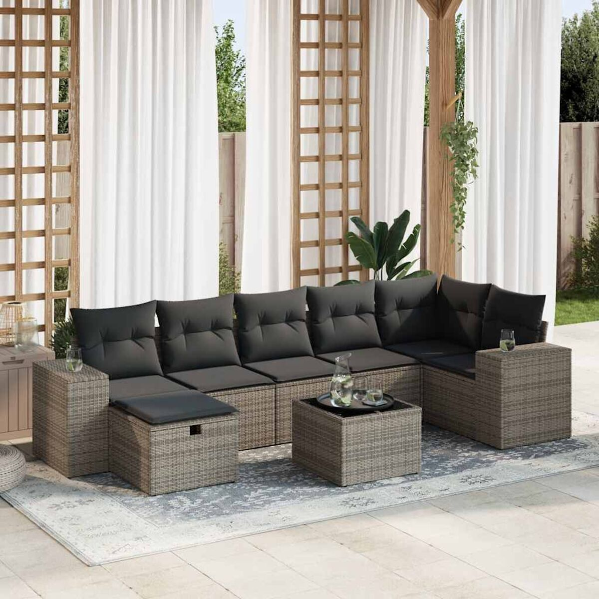 Un set da patio all'aperto con divano, tavolo e sedie. Lo sfondo è un giardino.