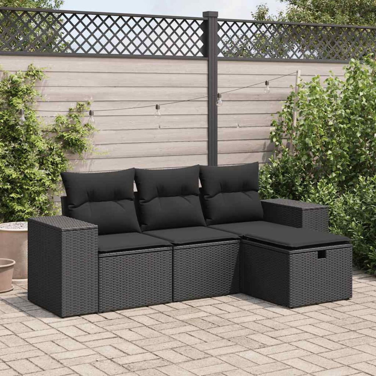Divano componibile in vimini nero con cuscini neri su un patio in mattoni.