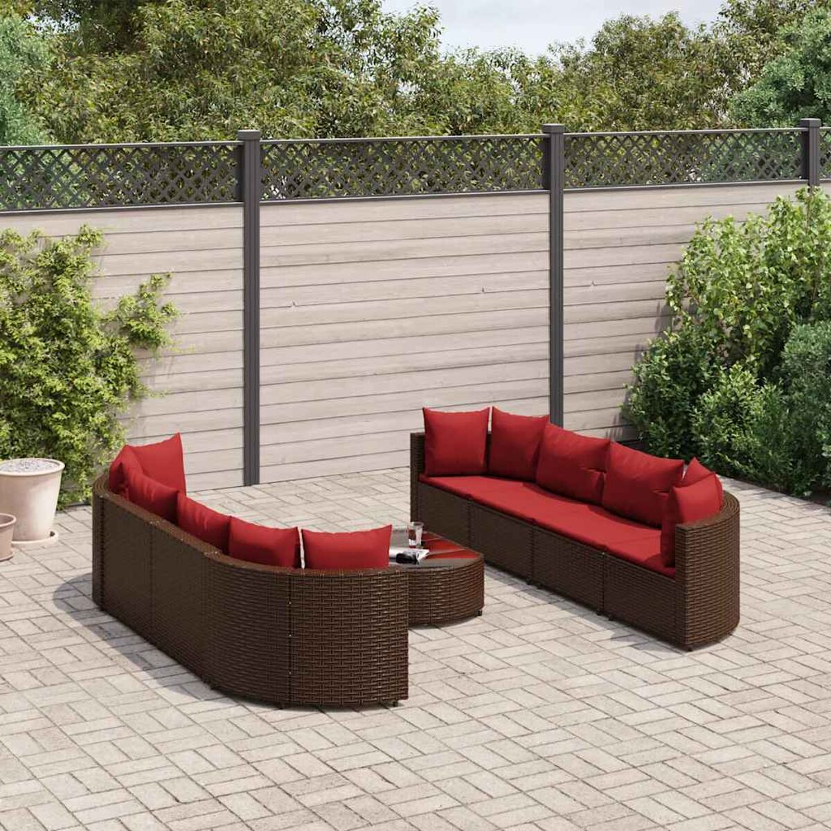 Conjunto de asientos al aire libre con cojines rojos. Incluye un sofá seccional y una mesa de centro, en un patio pavimentado.