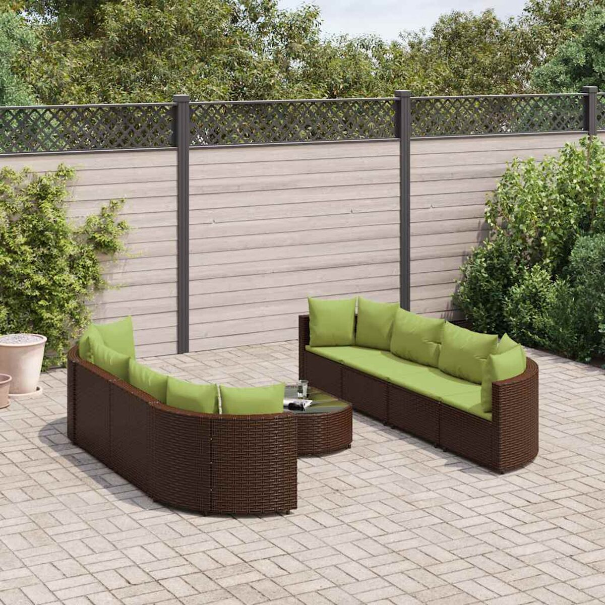 Zona de estar exterior con muebles tejidos marrones y cojines verdes. Incluye mesa y entorno de patio.