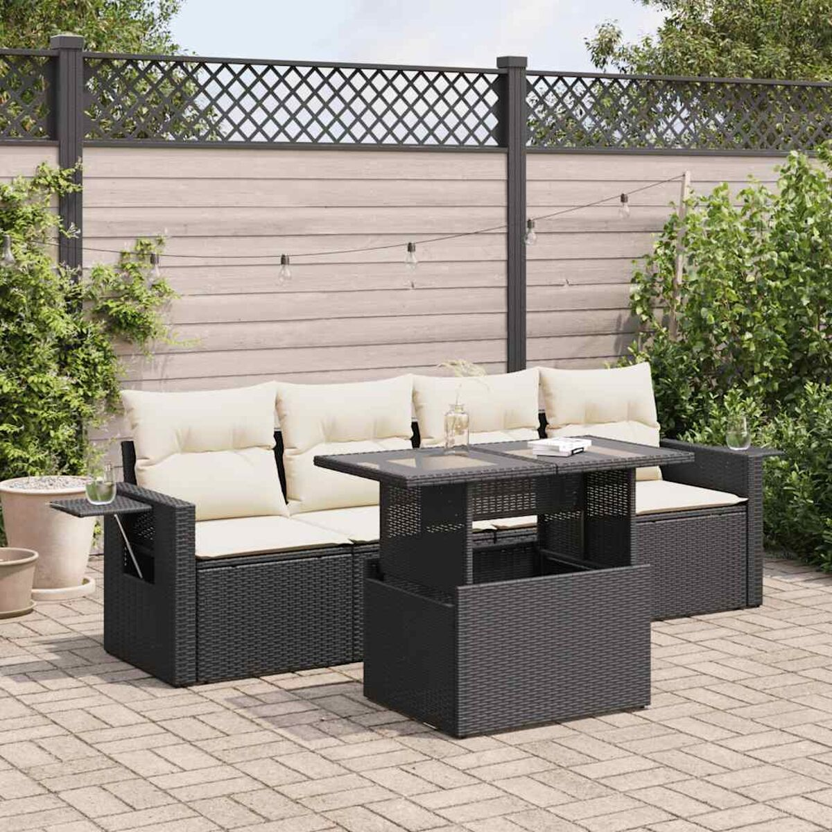 Divano in rattan nero con cuscini, tavolo e ambiente patio sul retro.