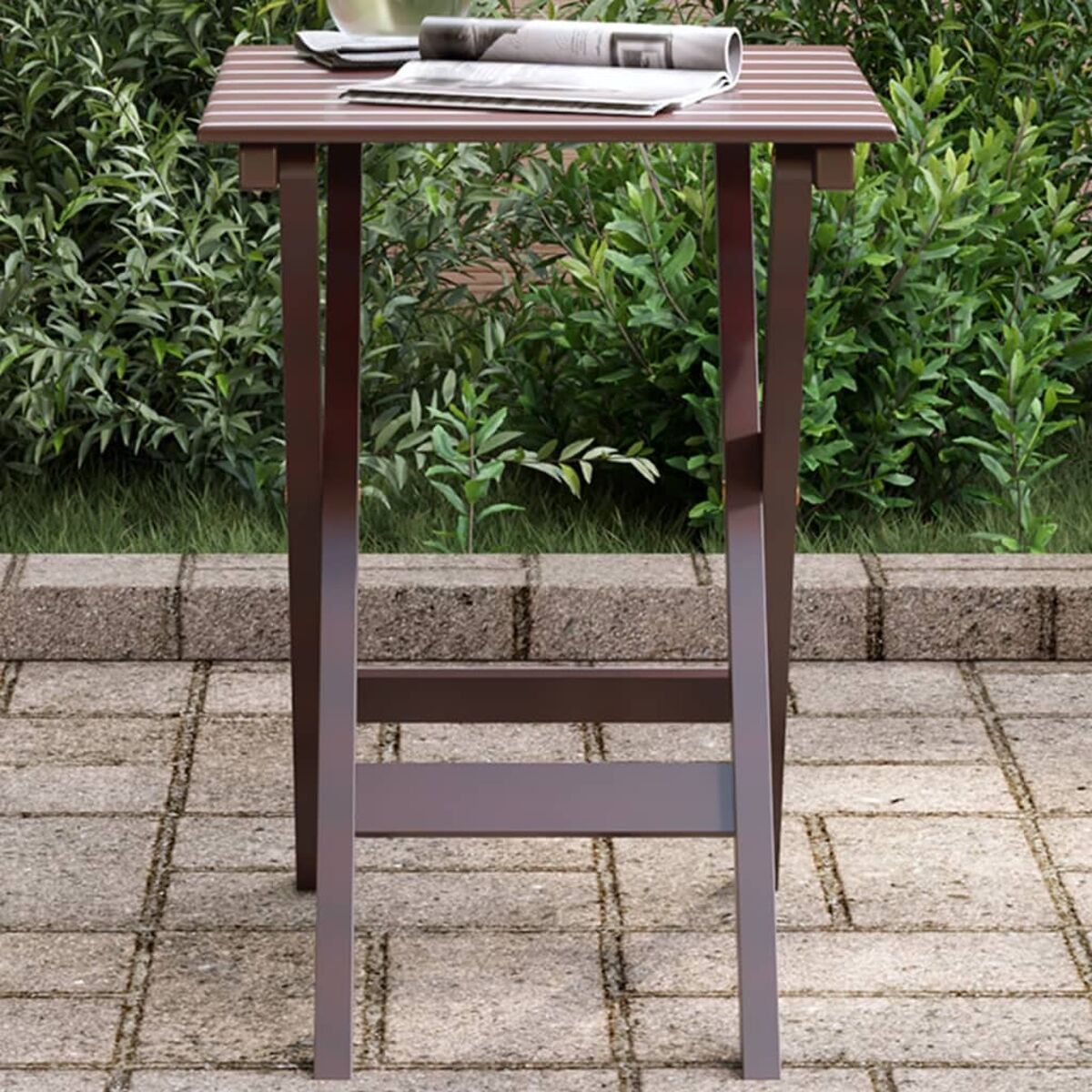 Un tavolino marrone con giornale e tazza, su un patio in pietra.