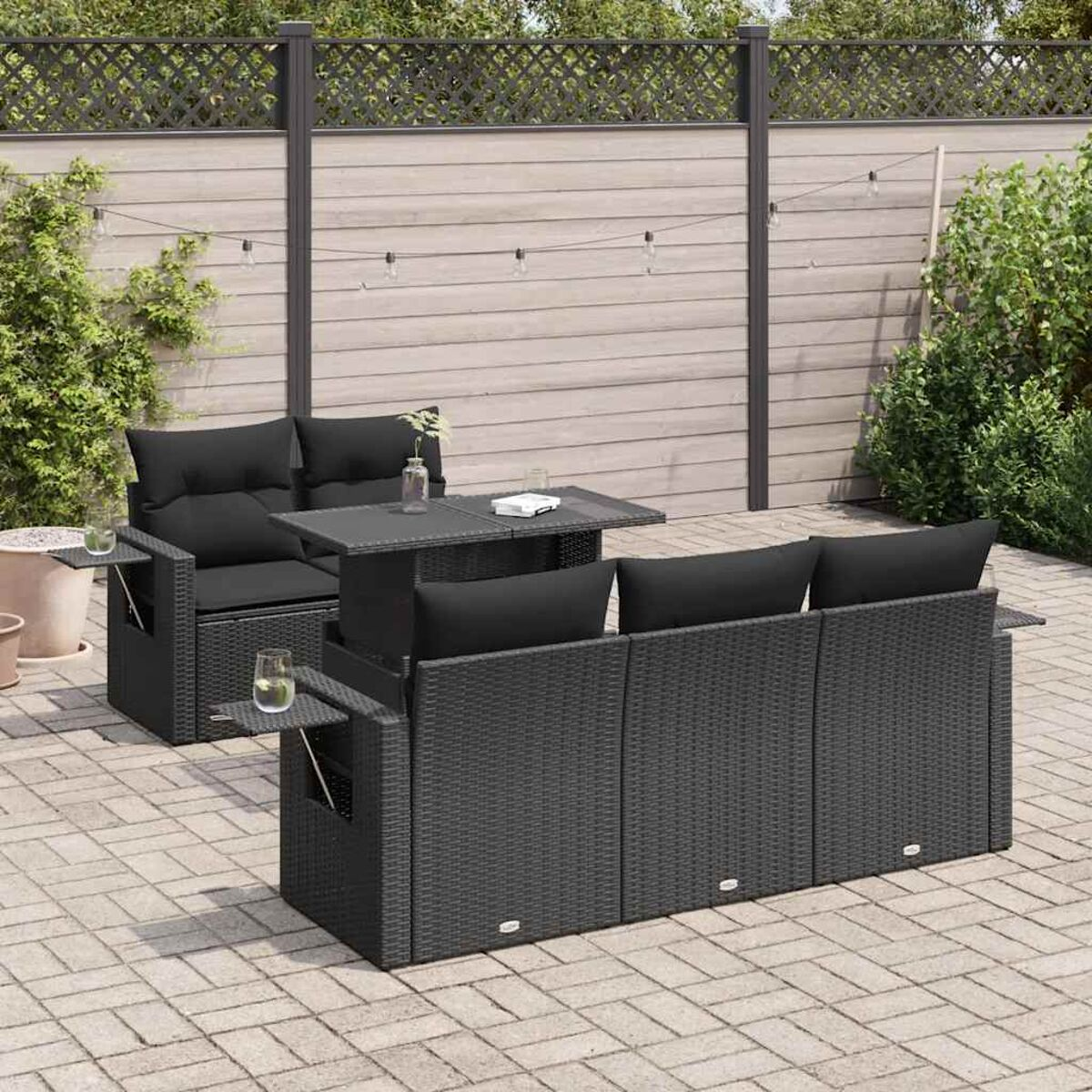 Schwarzes Rattan-Outdoor-Möbelset. Beinhaltet Sofa, Tisch und Stuhl. Schwarze Kissen. Gartenumgebung.
